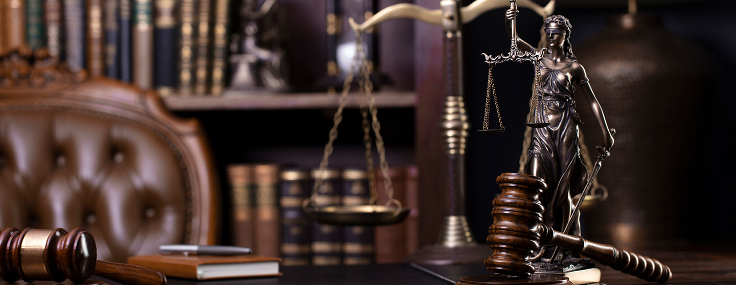 Lady Justice statue with scales and gavel on a desk, symbolizing law and justice.