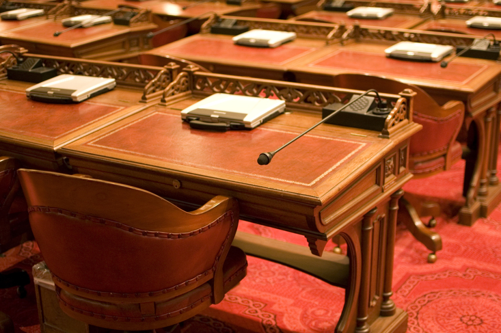 Elegant wooden desks with microphones in a formal meeting room setting.