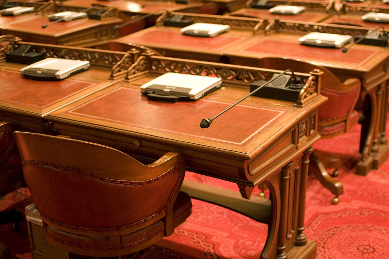 Elegant wooden desks with microphones in a formal meeting room setting.