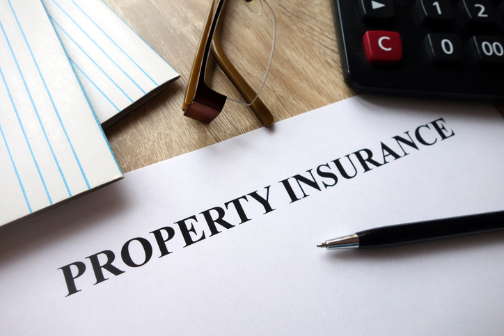 Property insurance document on desk with pen and calculator.