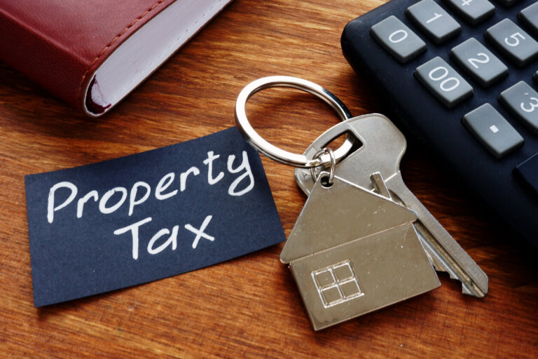 Property tax concept with house keychain and calculator on desk.