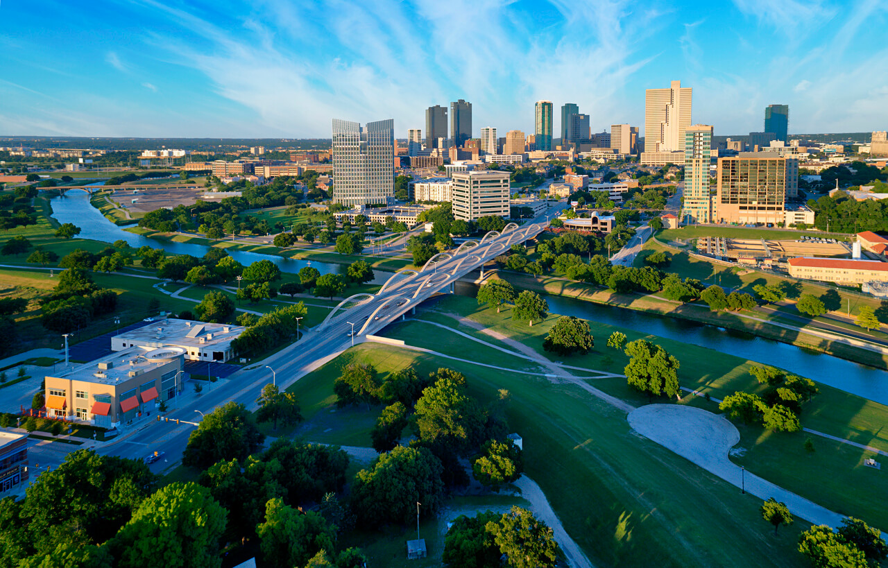 Aerial view of modern cityscape with lush green parks and waterways.