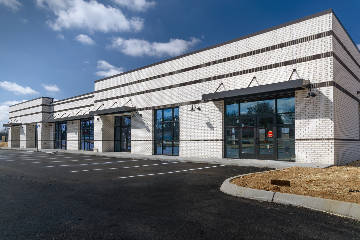 Modern empty retail building with large windows and parking lot
