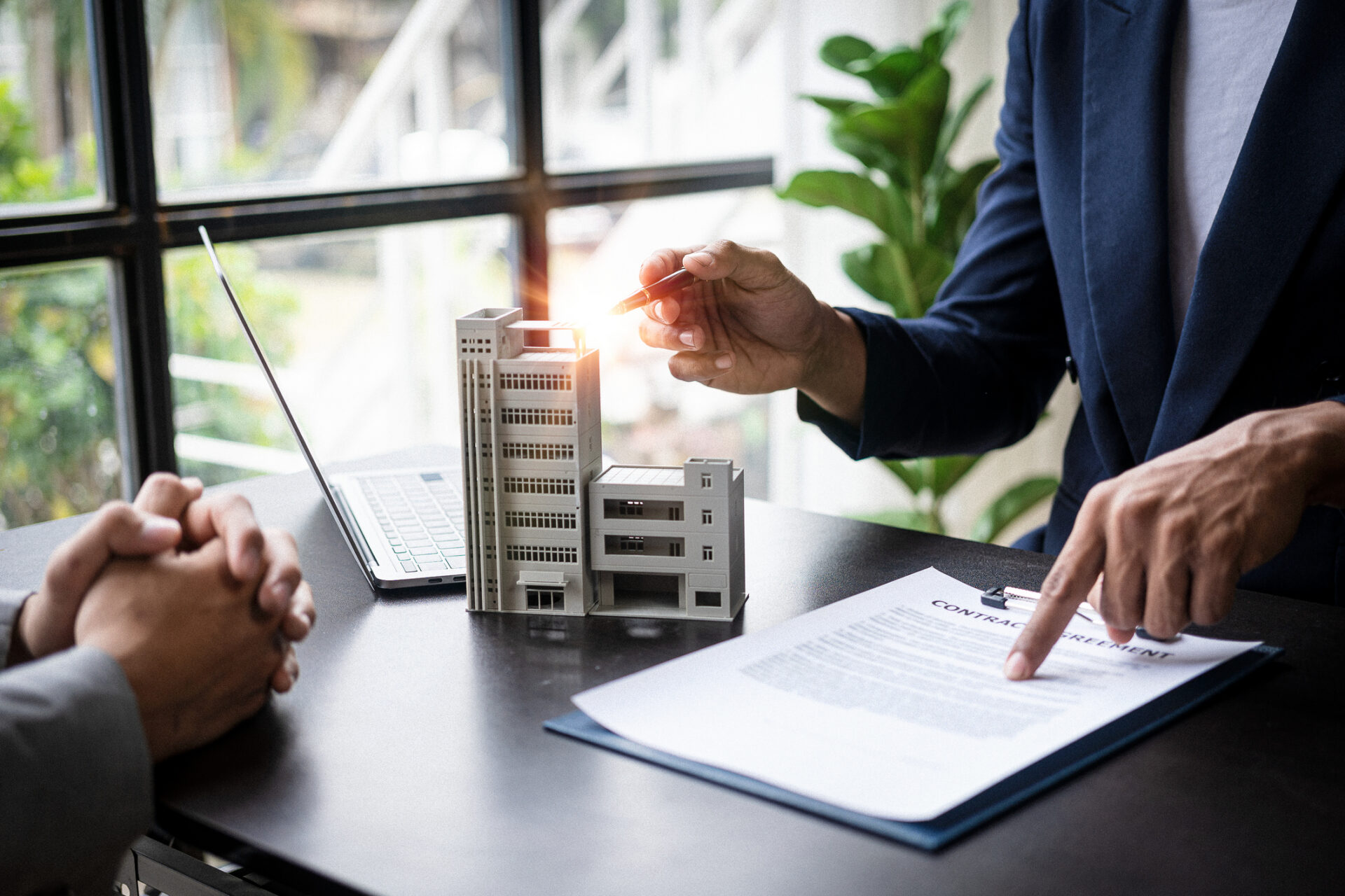 Business meeting with building model and contract discussion