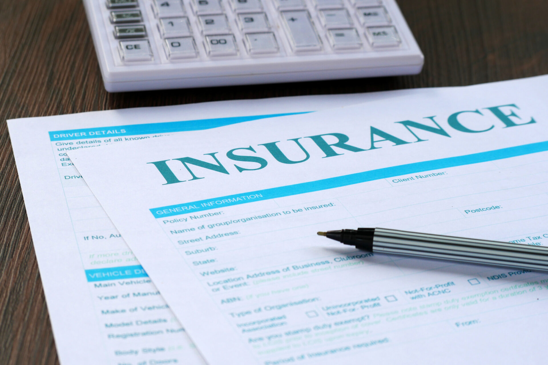 Close-up of an insurance form next to a pen on a desk.