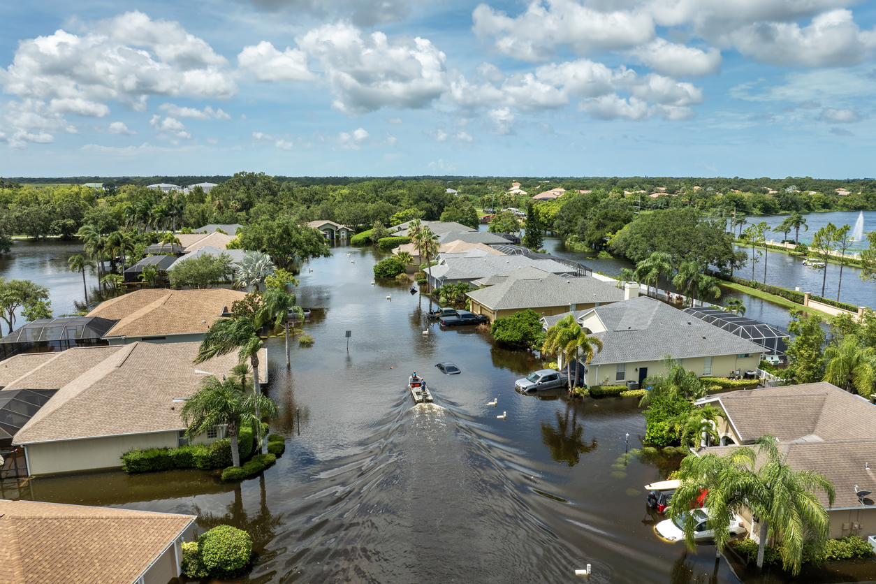 Aerial view of neighborhood flooded by storm, with houses and submerged cars.