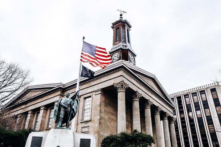 Historic building with a statue and American flag prominently displayed.