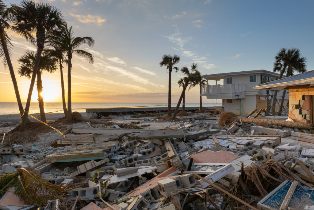 Destruction from a storm with debris surrounding damaged beachfront houses.
