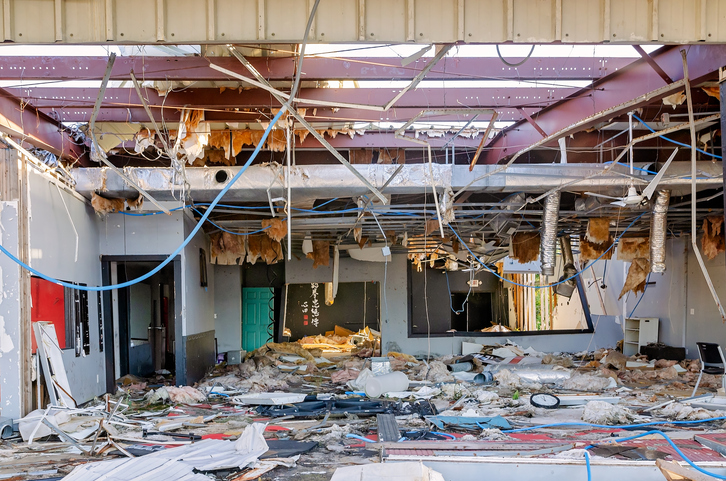 Interior view of a partially demolished building with debris and exposed beams.