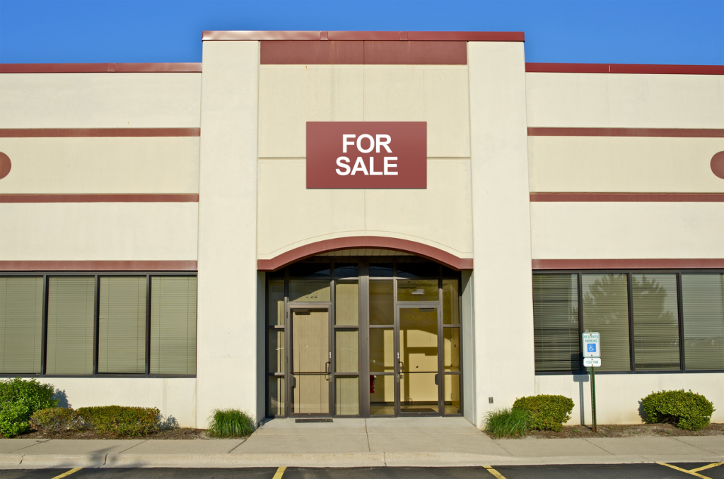 Commercial building with 'for sale' sign over entrance.