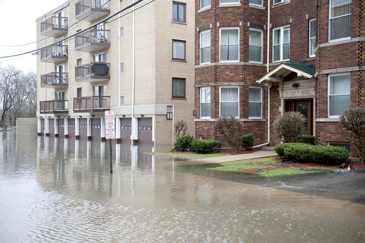 Flooded street near residential brick buildings after heavy rain