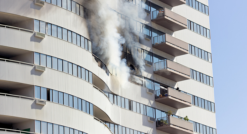 High-rise building with smoke from a fire on one of its balconies.