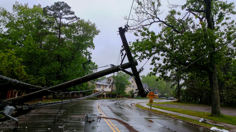 Fallen utility pole blocking a rainy suburban road